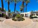 Circular entrance with a beautiful arrangement of palm trees, desert landscaping, and gate at 7272 E Gainey Ranch Rd # 23, Scottsdale, AZ 85258
