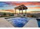 Stunning backyard oasis featuring a sparkling pool, jacuzzi, outdoor kitchen, and pergola under a breathtaking sunset sky at 826 E Buist Ave, Phoenix, AZ 85042