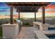 Backyard featuring a built-in grill, bar, and pergola overlooking a luxurious spa, set against a vibrant sunset at 826 E Buist Ave, Phoenix, AZ 85042