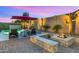 Inviting backyard featuring a pool, fire pit, comfortable seating, and illuminated cactus art, perfect for outdoor entertaining at 13820 W Weaver Ct, Litchfield Park, AZ 85340
