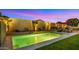 Stunning backyard pool featuring lush landscaping, comfortable seating, and a tranquil waterfall under the evening sky at 13820 W Weaver Ct, Litchfield Park, AZ 85340