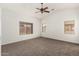 Spacious bedroom features a ceiling fan, neutral carpet, and natural light from three windows at 15460 W Mescal W St, Surprise, AZ 85379