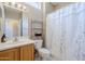 Bathroom featuring a vanity with sink, toilet, metal shelves, and a bathtub with floral shower curtain at 15960 W Indigo Ln, Surprise, AZ 85374