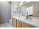 Well-lit bathroom features double sinks, wood cabinetry and white tile flooring at 15960 W Indigo Ln, Surprise, AZ 85374