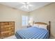 Cozy bedroom with a ceiling fan, a wooden bed frame, and a matching dresser with decorative lamp at 15960 W Indigo Ln, Surprise, AZ 85374