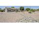 Home exterior showcasing neutral tones and desert landscaping with rock ground cover and mature trees at 15960 W Indigo Ln, Surprise, AZ 85374