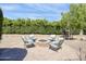 Outdoor brick fire pit with gravel, surrounded by comfy chairs and lush green privacy hedges at 16645 W Papago St, Goodyear, AZ 85338