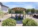 Cozy outdoor dining area covered by a rustic metal pergola and surrounded by greenery at 16645 W Papago St, Goodyear, AZ 85338