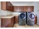 Convenient laundry room with gray washer and dryer, wooden cabinets, and tile countertops at 1707 E Carob Dr, Chandler, AZ 85286