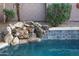 Swimming pool featuring rock waterfall, lush greenery, and tiled accents at 1707 E Carob Dr, Chandler, AZ 85286