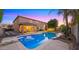Beautiful pool and backyard at dusk with patio, lighting, and lush greenery at 18518 E Ashridge Dr, Queen Creek, AZ 85142