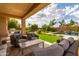 Spacious covered patio featuring comfortable seating, a marble table, and a view of the lush backyard and pool at 2308 E Dry Wood Rd, Phoenix, AZ 85024