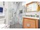 Modern bathroom featuring a glass-enclosed shower with tiled walls, wooden vanity and silver fixtures, offering style and comfort at 2308 E Dry Wood Rd, Phoenix, AZ 85024