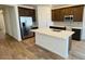 Modern kitchen features stainless steel appliances, granite countertops, an island with sink, and hardwood style floors at 25133 W Wayland Dr, Buckeye, AZ 85326