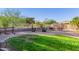 Lush backyard with green grass, desert landscaping, fire pit, and various seating areas at 26330 N 56Th Dr, Phoenix, AZ 85083