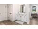Bright white bathroom features a vanity with black hardware, a mirror, and wood-style tile flooring at 2985 N Point Ridge Rd, Buckeye, AZ 85396