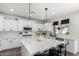 Bright, spacious kitchen featuring white cabinetry, a large island with seating, and modern lighting fixtures at 2985 N Point Ridge Rd, Buckeye, AZ 85396