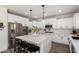 Modern, all-white kitchen with stainless steel appliances, a large island, and stylish pendant lighting at 2985 N Point Ridge Rd, Buckeye, AZ 85396