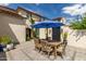 Lovely outdoor courtyard featuring a wooden dining table, six chairs, and a shaded patio umbrella at 2985 N Point Ridge Rd, Buckeye, AZ 85396