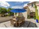 Picturesque patio with a wooden table, six chairs, a large blue umbrella, and manicured plants at 2985 N Point Ridge Rd, Buckeye, AZ 85396