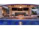 Amazing swim-up bar with a fireplace, outdoor TVs, and ample seating, perfect for entertaining guests at 2985 N Point Ridge Rd, Buckeye, AZ 85396