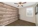 Comfortable bedroom featuring neutral walls, ceiling fan, wood accent wall and window with shutters at 3048 W Thorn Tree Dr, Phoenix, AZ 85085