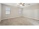 The large bedroom with neutral carpet boasts two windows and a ceiling fan at 30776 W Earll Dr, Buckeye, AZ 85396