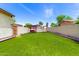 Backyard featuring artificial grass, seating, and a high block wall for privacy at 3819 N Springfield St, Buckeye, AZ 85396