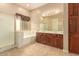 Bright bathroom featuring double sinks, a separate shower, a soaking tub, and wood cabinets at 3819 N Springfield St, Buckeye, AZ 85396
