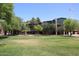 Exterior view of a baseball field and outfield set against a blue sky surrounded by green grass and mature trees at 4317 N 70Th St, Scottsdale, AZ 85251