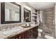 Elegant bathroom featuring double sinks, granite countertops, dark wood cabinetry, and stone shower at 5110 E Mark Ln, Cave Creek, AZ 85331