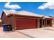 Charming single-story home featuring a red garage door, desert landscaping, and a white tiled roof at 6302 E Portia St, Mesa, AZ 85215