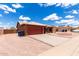 Charming single-story home featuring a red garage door, desert landscaping, and a white tiled roof at 6302 E Portia St, Mesa, AZ 85215