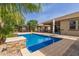Relaxing backyard pool features stone detailing, ample space, and a covered patio area with a built-in grill at 1036 W Siebold Tree Ave, Queen Creek, AZ 85140