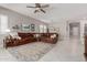 Well decorated living room with sectional, tiled floors, fan, and open to dining area and kitchen at 1036 W Siebold Tree Ave, Queen Creek, AZ 85140