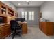 Bright home office features built-in desk and cabinets, a ceiling fan, and large windows with lovely shutters at 1036 W Siebold Tree Ave, Queen Creek, AZ 85140