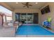 Covered patio area with comfortable seating, ceiling fan, and large sliding glass doors to the home interior at 1036 W Siebold Tree Ave, Queen Creek, AZ 85140