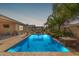 Sparkling pool with stone accents and lush landscaping creates a serene backyard oasis with a covered seating area at 1036 W Siebold Tree Ave, Queen Creek, AZ 85140
