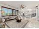 Bright living room with white tile flooring, large windows, neutral decor, and ceiling fan at 11737 N 143Rd Dr, Surprise, AZ 85379