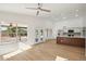 Bright living room featuring light wood floors, a ceiling fan, and an open layout to the modern kitchen at 12217 W Edgemont Ave, Avondale, AZ 85392