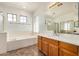 Bathroom features a bathtub, a shower with glass doors, and a dual sink vanity with wood cabinets at 13599 W Monte Vista Rd, Goodyear, AZ 85395