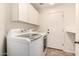 Well-equipped laundry room with white cabinets, a utility sink, and appliances at 13599 W Monte Vista Rd, Goodyear, AZ 85395