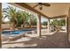 Covered patio overlooking a sparkling pool and a tropical landscaped backyard at 13599 W Monte Vista Rd, Goodyear, AZ 85395