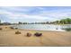 Scenic view of the community lake, featuring sandy beach, park benches, and an abundance of waterfowl on a partly cloudy day at 16186 W Port Royale Ln, Surprise, AZ 85379