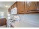 View of the kitchen and white appliances with wooden cabinets and white countertops at 16186 W Port Royale Ln, Surprise, AZ 85379