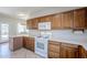 Kitchen with white appliances, wooden cabinets, and access to the backyard at 16186 W Port Royale Ln, Surprise, AZ 85379