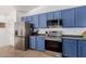 Well-equipped kitchen with stainless steel refrigerator, oven, and blue cabinets at 16526 W Desert Ln, Surprise, AZ 85388