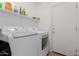 A neatly organized laundry room with modern washer and dryer units and storage shelves at 16526 W Desert Ln, Surprise, AZ 85388