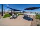 Community area with tables, chairs, and umbrellas near the pool with lounge chairs at 17831 W Pasadena Ave, Litchfield Park, AZ 85340