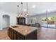 Open-concept kitchen with a granite island, pendant lighting, and views to a living room and outdoor pool at 1904 E Grand Canyon Dr, Chandler, AZ 85249